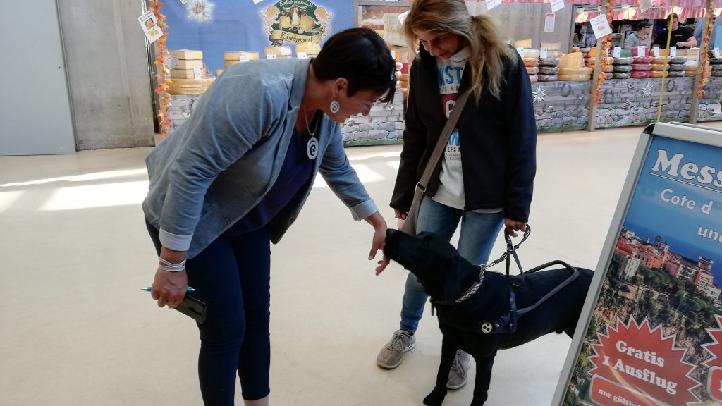 Eine Dame begrüßt ein Reha-Hund auf einer Messe